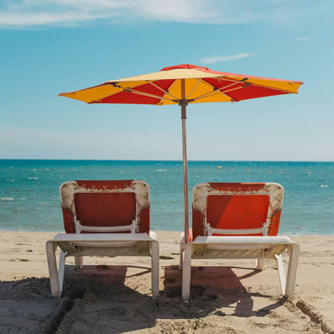 Chairs on the beach under an umbrella.