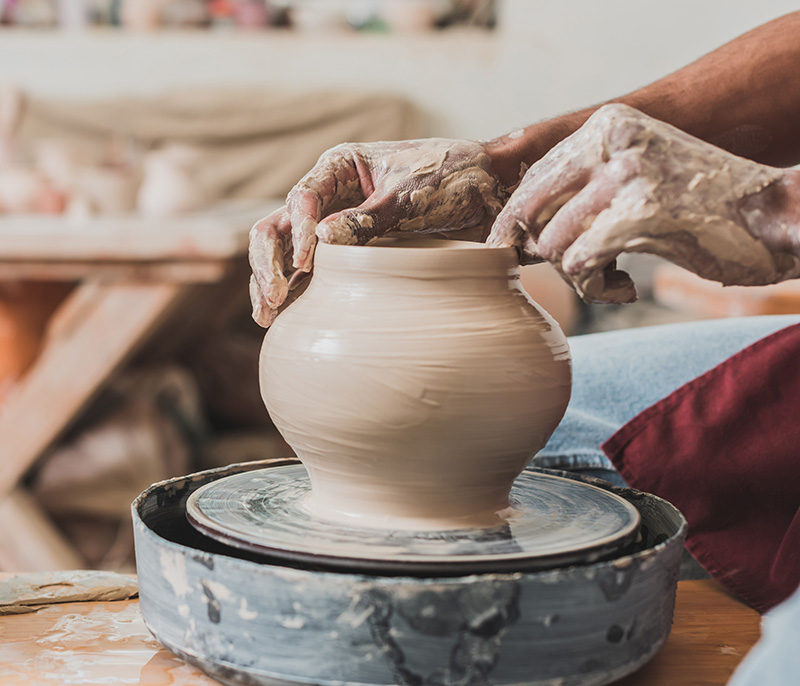 Hands shaping a pot on a pottery wheel